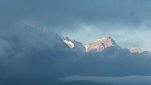 Snowy mountains, partly covered by clouds, partly in the sunshine