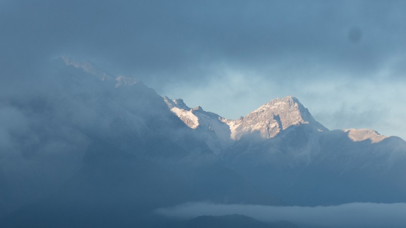 Snowy mountains, partly covered by clouds, partly in the sunshine